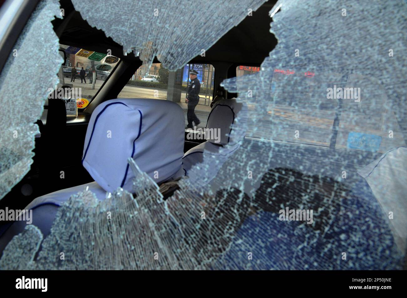 A Chinese police officer is framed by the glass window of a vehicle damaged by explosions outside the provincial headquarters of China's ruling Communist Party in Taiyuan in north China's Shanxi province Wednesday Nov. 6, 2013. The Shanxi provincial government and police said the blasts which killed one and injured eight struck at about 7:40 a.m. (2340 GMT Tuesday). (AP Photo) CHINA OUT Stockfoto