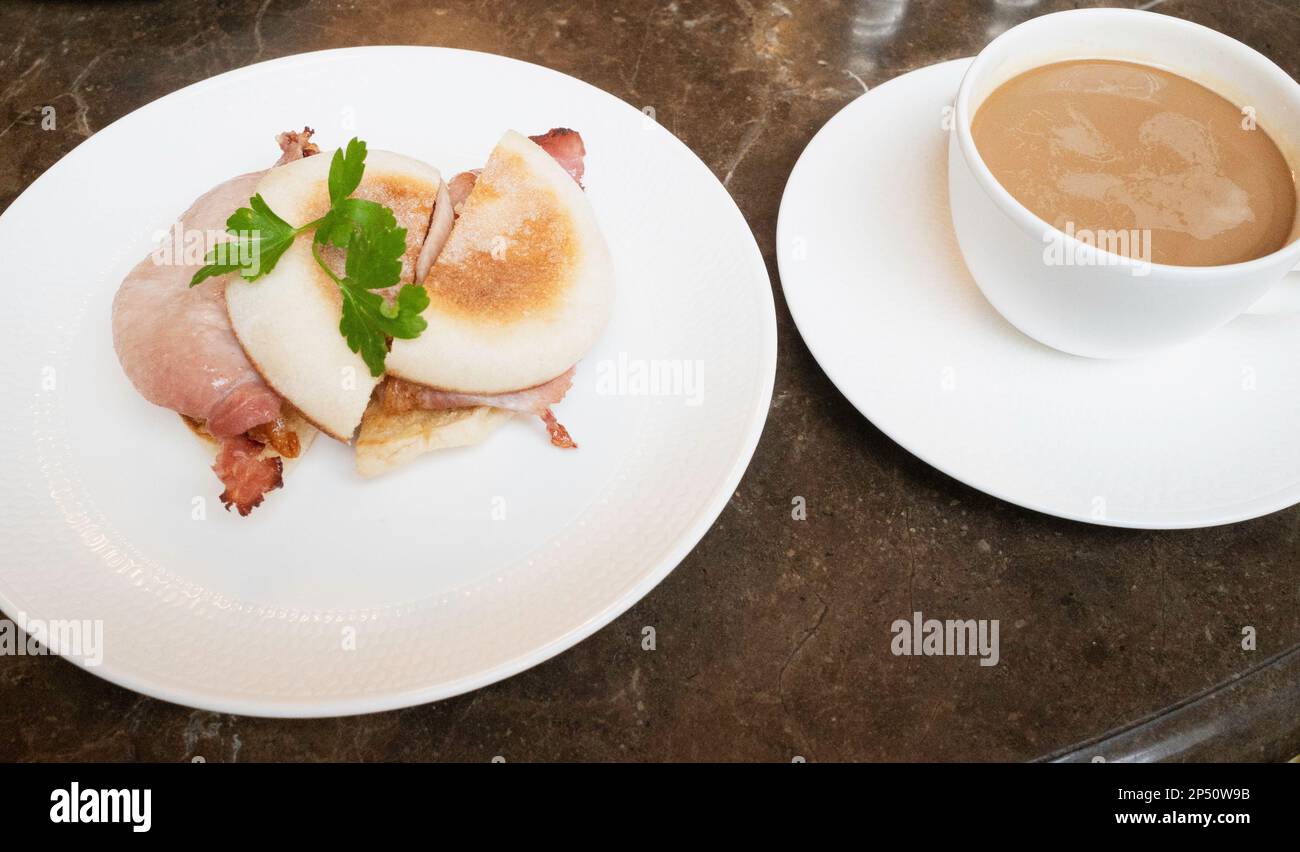 Morgendlicher Snack in Betty's Café Frühstücks-Muffins mit Speck und einer kleinen Tasse Americano-Kaffee Stockfoto