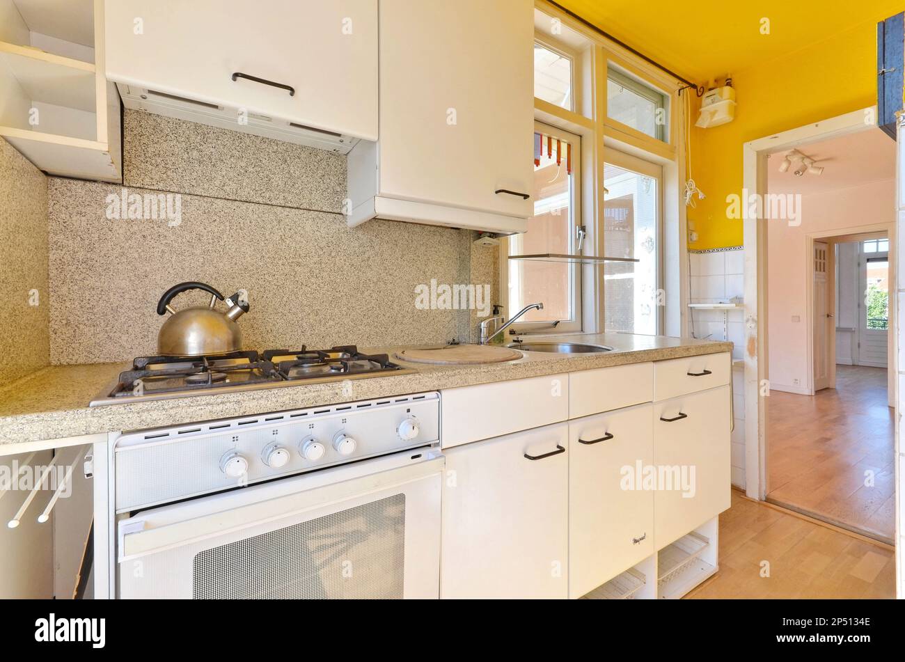 Eine Küche mit gelben Wänden und weißen Geräten auf dem Herd, in einem offenen Raum, der seit vielen Jahren genutzt wird Stockfoto