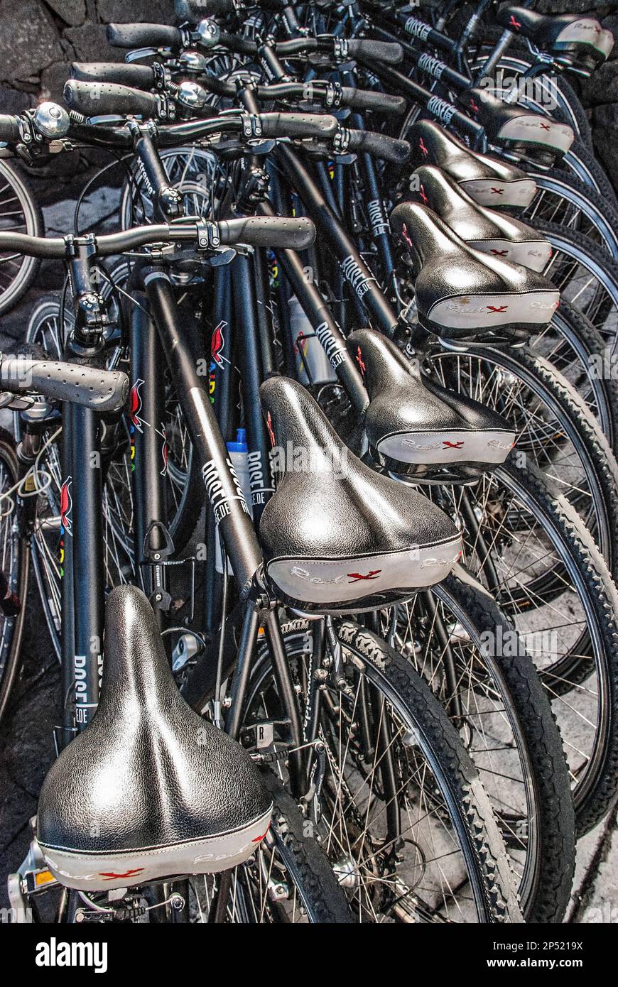 Gruppe sehr ähnlicher schwarzer Fahrräder, die auf der Insel La Palma auf den Kanarischen Inseln gemietet oder genutzt werden können. Stockfoto
