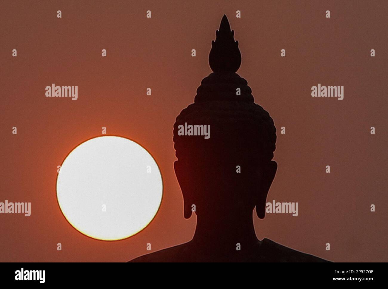 Nakhon Pathom, Thailand. 06. März 2023. Die Sonne geht hinter einer großen Buddha-Statue während der Feier in einem Tempel unter. Makha Bucha Day ehrt Buddha und seine Lehren, es fällt auf den Vollmondtag des dritten Mondmonats. Kredit: SOPA Images Limited/Alamy Live News Stockfoto