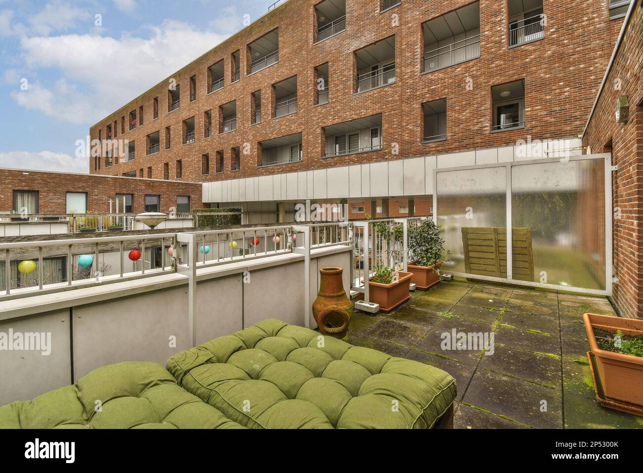 Amsterdam, Niederlande - 10. April 2021: Ein Außenbereich mit Sofas und Pflanzen auf dem Balkon vor einem weiß bemalten Ziegelgebäude Stockfoto