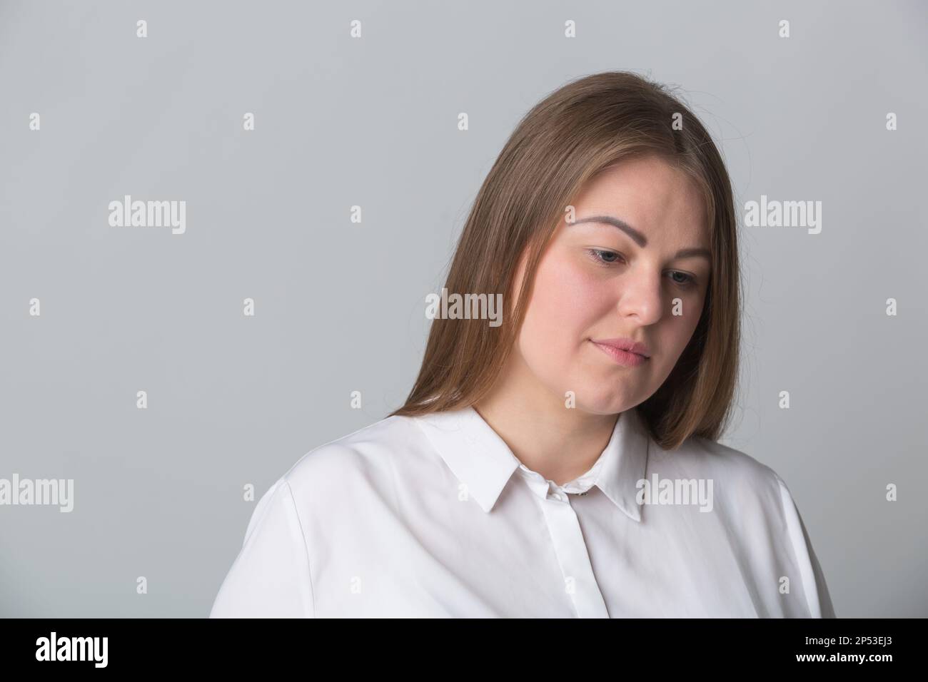 Studioporträt einer unglücklichen, übergewichtigen Frau. Junge Erwachsene ukrainische Frau, die frustriert nach unten schaut Stockfoto