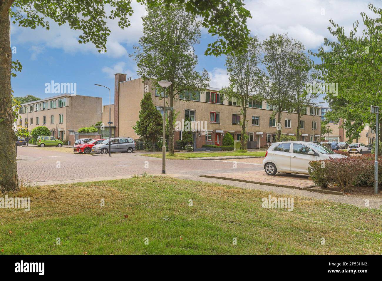 Ein Apartmentkomplex mit Autos, die auf der Straße geparkt sind und Bäume im Vordergrund - Bild stammt von google Earth Stockfoto
