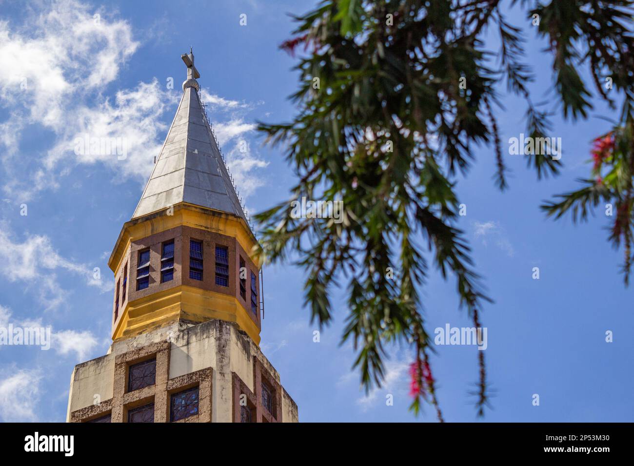 Goiania, Goias, Brasilien – 05. März 2023: Der Gipfel des Turms der Metropolitan Cathedral of Goiania zwischen blühenden Zweigen eines Baumes. Stockfoto