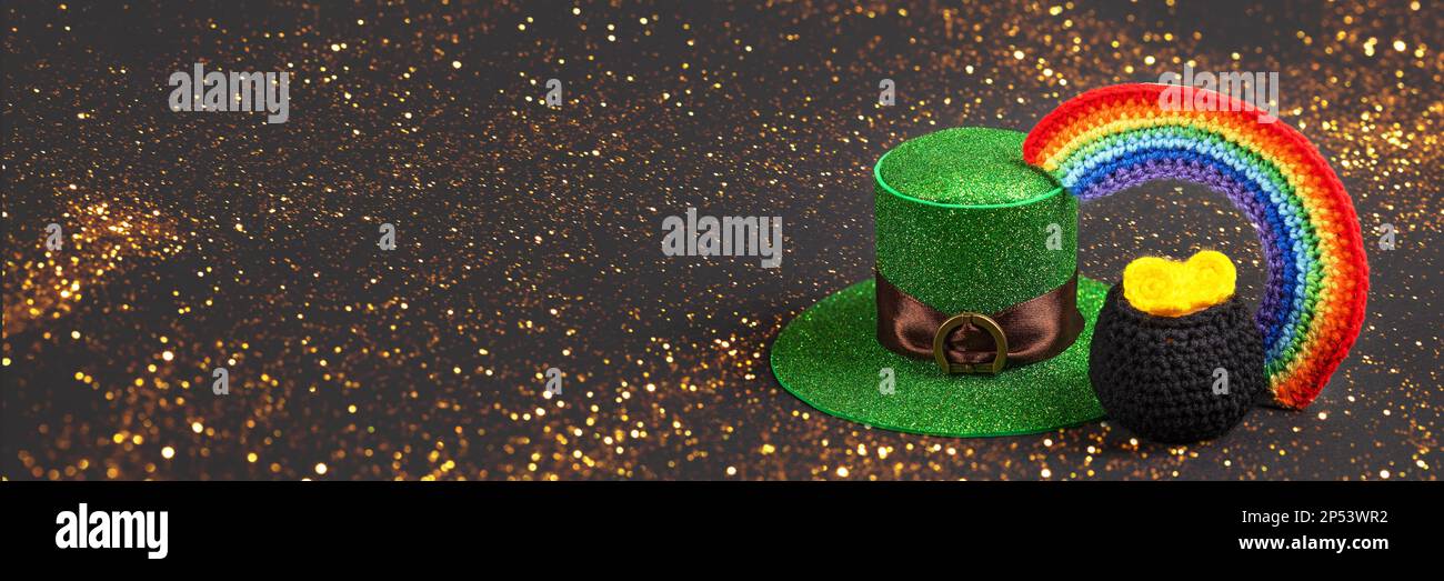 St. Patrick's Day Konzept. Banner mit grünem Hut, schwarzer gestrickter Kessel mit Münzen und einem sieben-farbigen hellen Regenbogen auf schwarzem Hintergrund. Postkarte Stockfoto