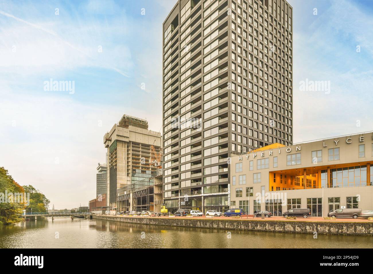 Amsterdam, Niederlande - 10. April 2021: Eine Stadt mit Gebäuden auf beiden Seiten und Wasser im mittleren Teil des Flusses, der durch ihr Zentrum fließt Stockfoto