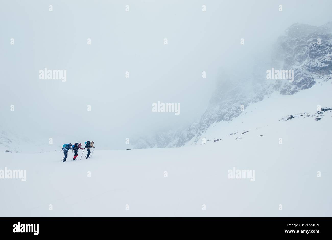 Drei Mitglieder des Seilteams steigen auf den Wintergipfel der hohen Berge. Blizard, der das strukturelle Becken in den Bergen der Vysoke Tatry (hohe Tatra) unter L bedeckt Stockfoto