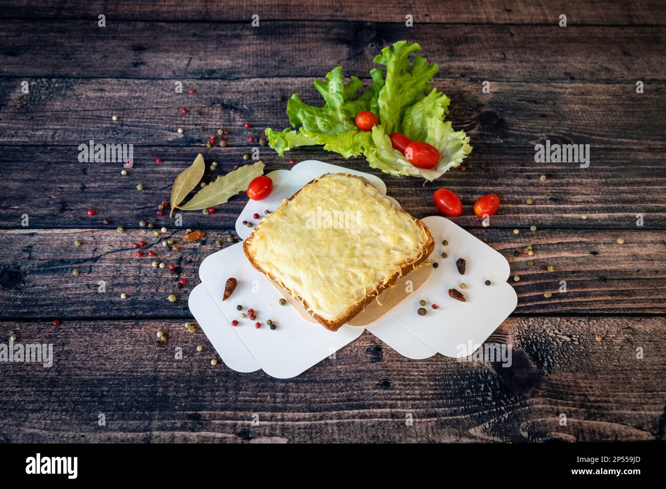 Gegrilltes Croque monsieur mit geschmolzenem Käse, serviert auf einem Holzboden Stockfoto