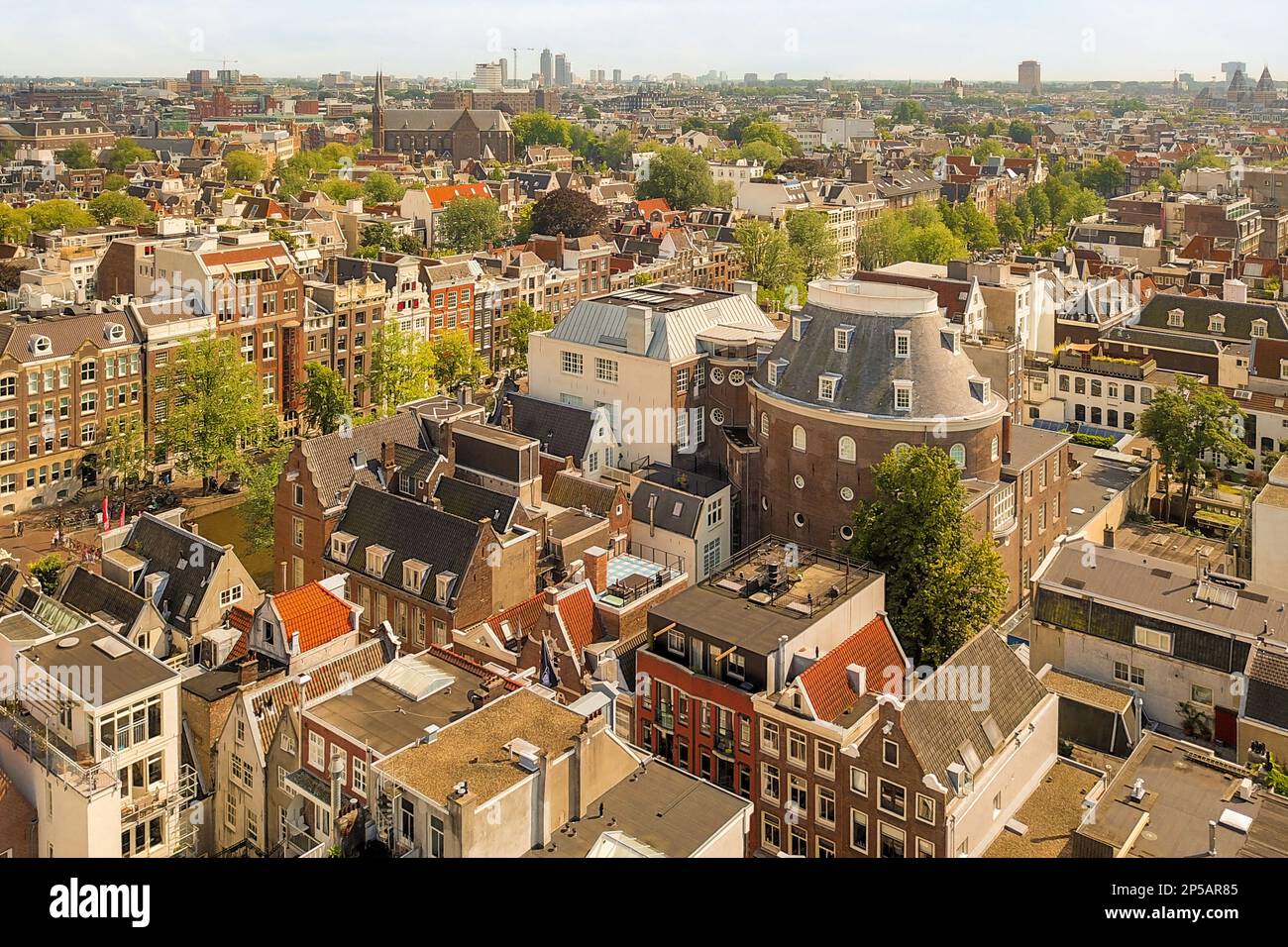 Amsterdam, Niederlande - 10. April 2021: Eine Stadt von der Spitze eines Gebäudes mit vielen Gebäuden in der Mitte des Bildes und Bäumen auf der anderen Seite Stockfoto