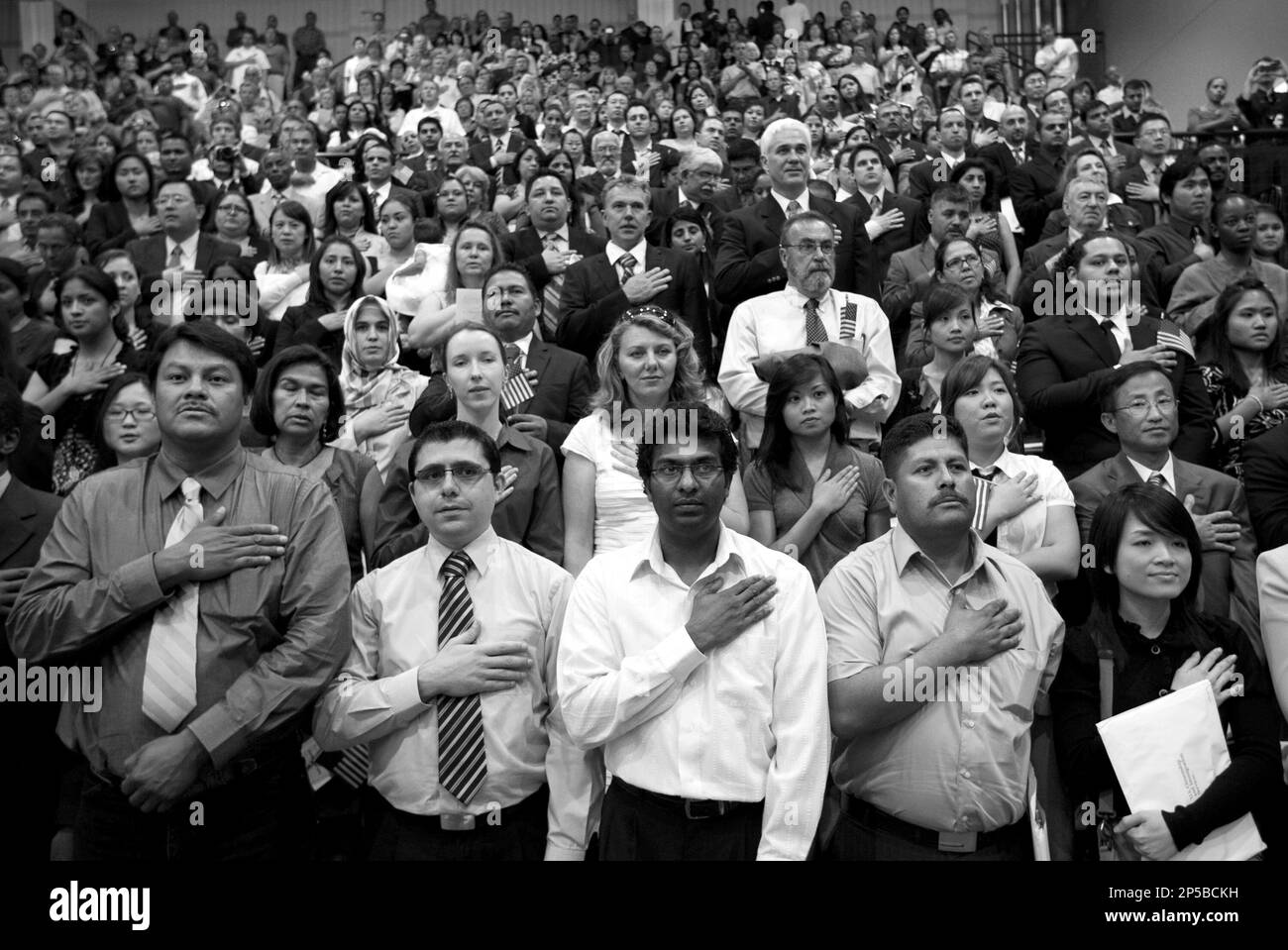 New American citizens say the Pledge of Allegiance after taking the oath of citizenship at a U.S. naturalization ceremony at the Delco Center on Tuesday April 26, 2011. The ceremony had 984 new Americans from 105 different countries. On the front row are left to right, Rogelio Jimenez, originally from Mexico and now living in Austin, Telad Malouhi, origianlly from Syria and now living in Round Rock, Janak Jayakody, originally from Sri Lanka and now living in Austin, Jose Barcenas, originally from Mexico and now living in Killeen, and My Vo, originally from Vietnam and now living in Austin. (AP Stockfoto