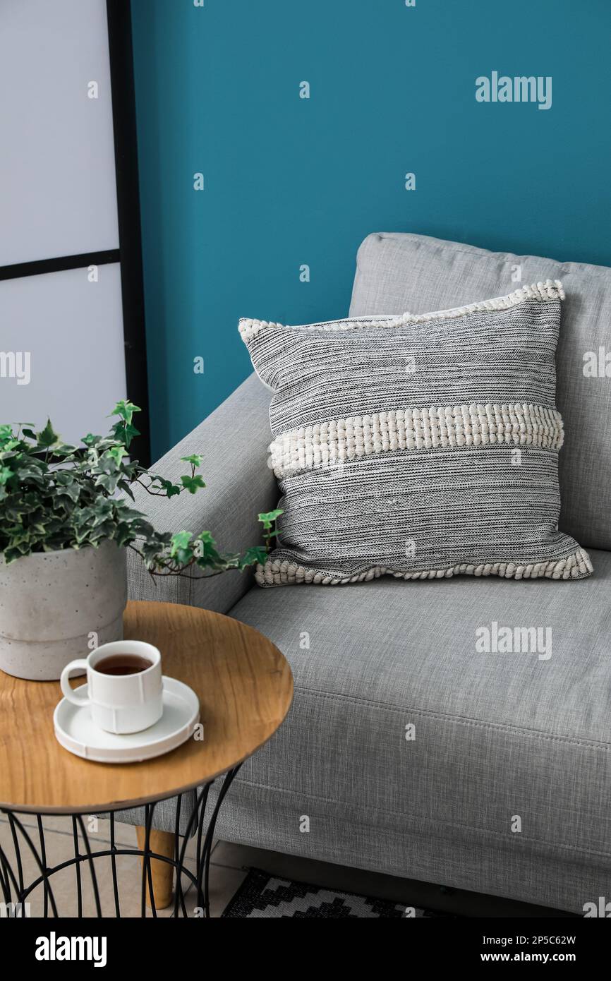Graues Sofa mit Kissen und einer Tasse Kaffee auf dem Tisch nahe der blauen  Wand Stockfotografie - Alamy