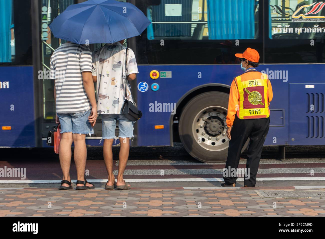 BANGKOK, THAILAND, FEBRUAR 04 2023, Touristen warten auf die Anweisung der Wache, die Straße sicher zu überqueren Stockfoto