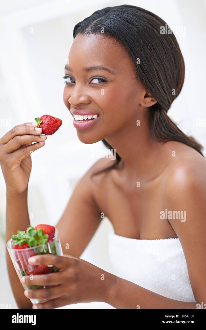 Ich kann einfach nicht genug bekommen. Eine schöne junge Frau, die Erdbeeren isst. Stockfoto