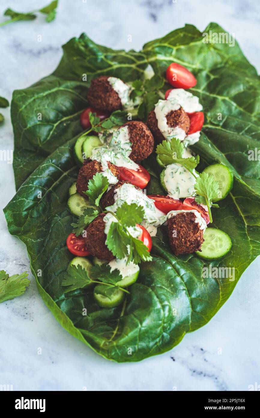 Falafel Wrap mit Gemüse und Tahini auf grünem Mangold. Alternatives veganes Rezept. Stockfoto