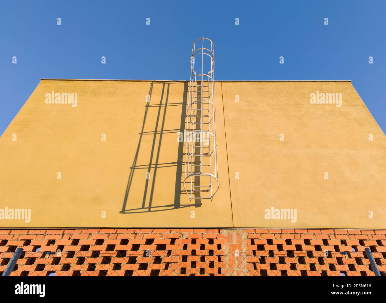 Wartungsleiter auf einem im Bau befindlichen Gewerbegelände. Blauer Himmelshintergrund Stockfoto