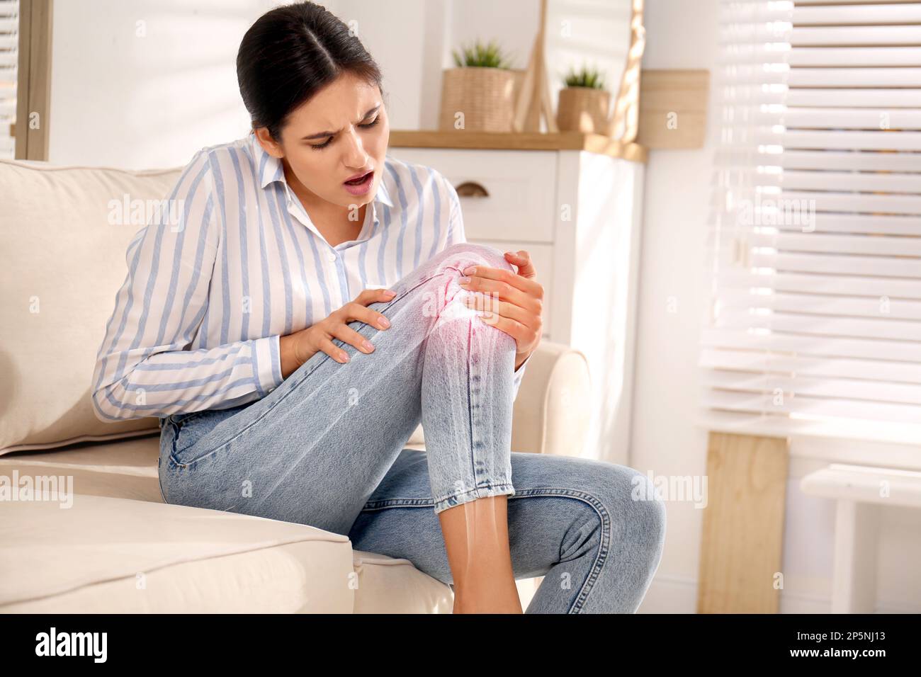 Eine kranke junge Frau zu Hause. Digitale Komposition mit Darstellung des Kniegelenkes Stockfoto