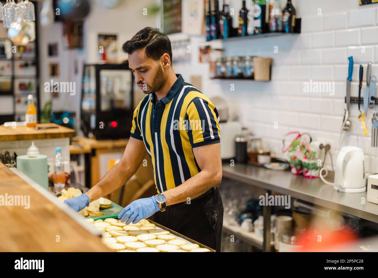 Junger Mann, der in der kommerziellen Küche frisches Essen zubereitet Stockfoto