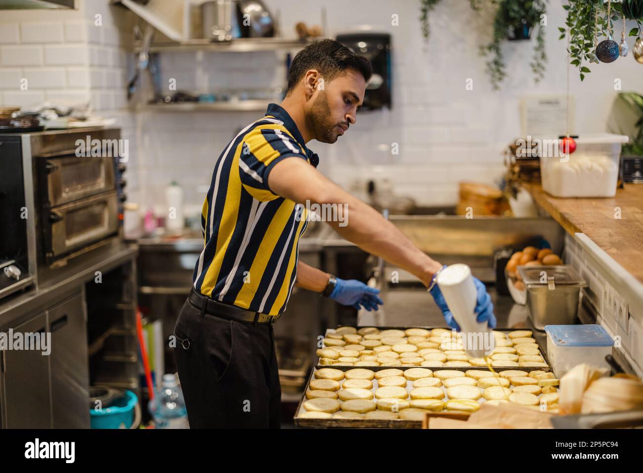 Junger Mann, der in der kommerziellen Küche frisches Essen zubereitet Stockfoto