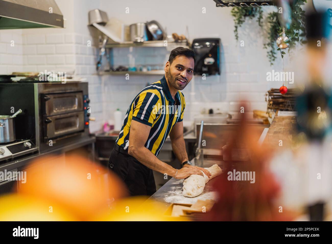 Junger Mann, der in der kommerziellen Küche frisches Essen zubereitet Stockfoto