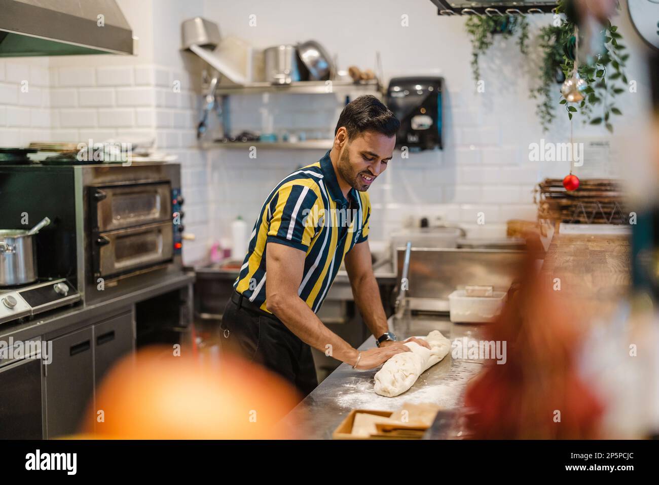Junger Mann, der in der kommerziellen Küche frisches Essen zubereitet Stockfoto