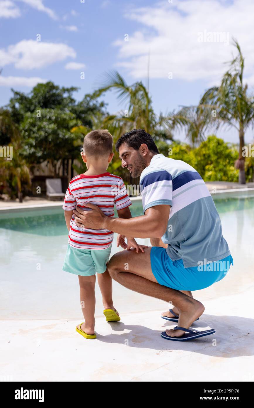 Fröhlicher, birassischer Vater und Sohn, die sich am Pool umarmen Stockfoto