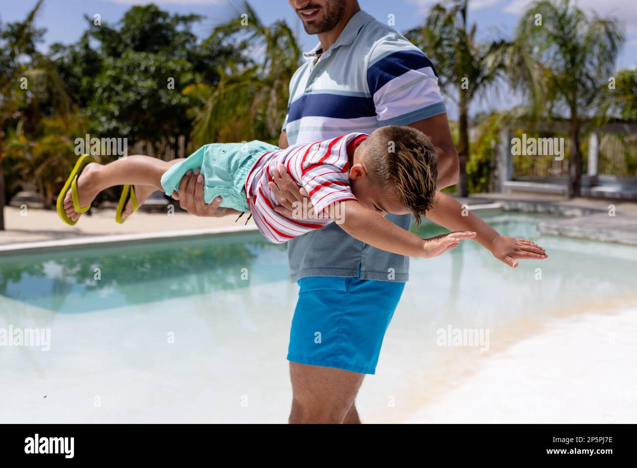 Fröhlicher, birassischer Vater und Sohn, die am Pool spielen Stockfoto