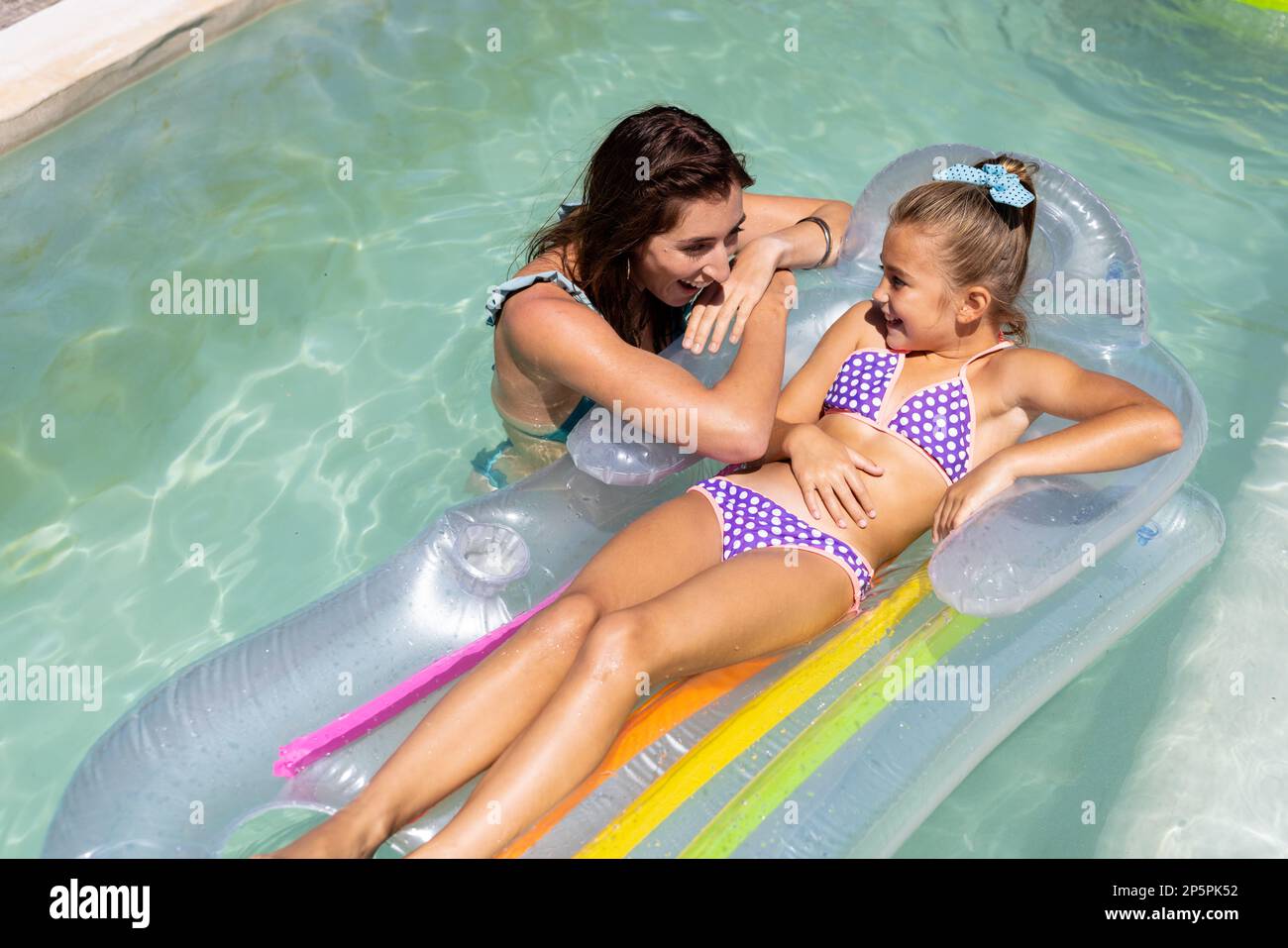 Glückliche, birassische Mutter und Tochter, die zusammen im Swimmingpool spielen Stockfoto