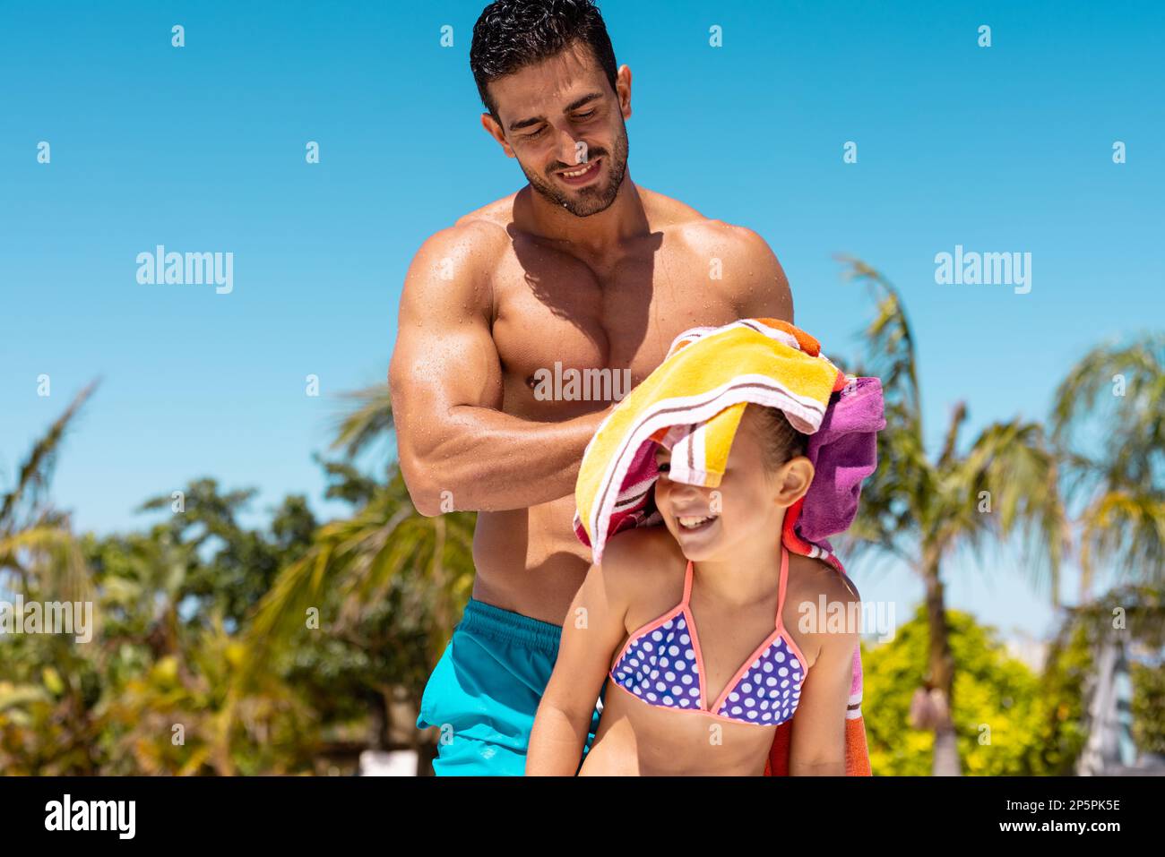 Glücklicher, birassischer Vater und Tochter, die ein Handtuch am Pool benutzten Stockfoto