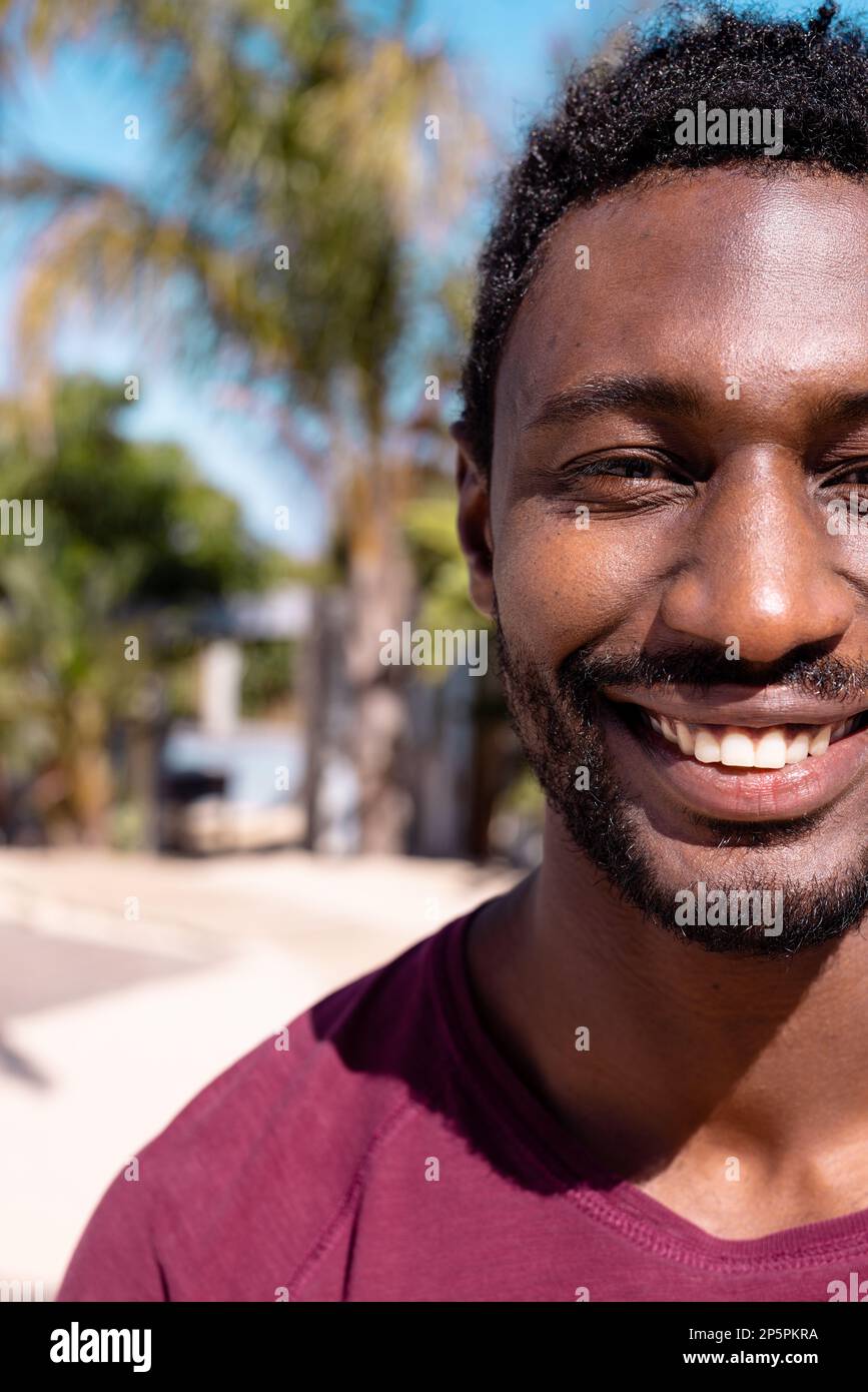 Porträt eines glücklichen afroamerikanischen Mannes, der in die Kamera schaut und am Strand lächelt, mit Kopierraum Stockfoto