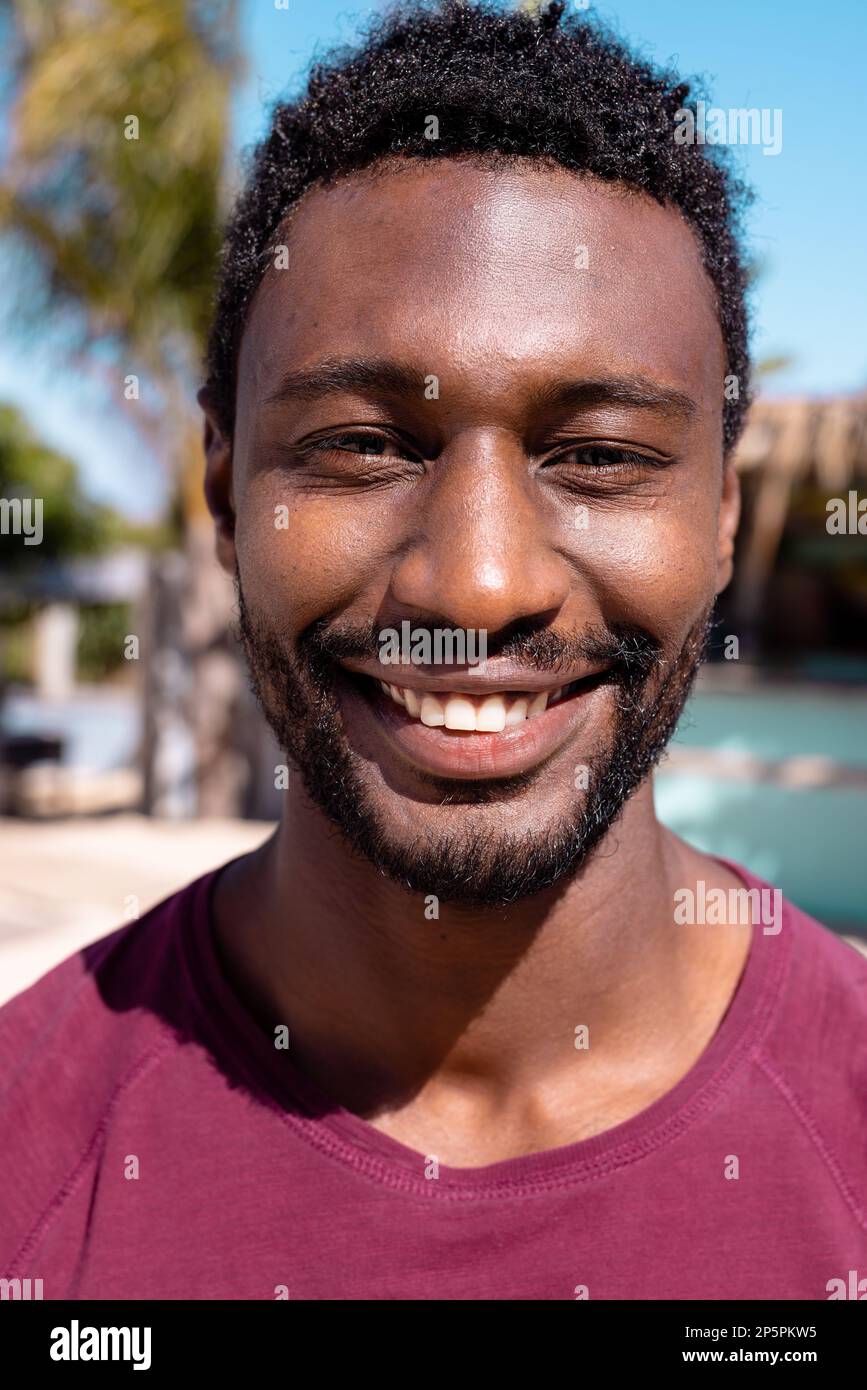 Porträt eines glücklichen afroamerikanischen Mannes, der in die Kamera schaut und am Strand lächelt Stockfoto