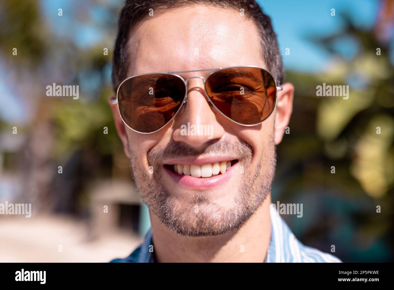Porträt eines glücklichen weißen Mannes, der in die Kamera schaut und am Strand lächelt Stockfoto