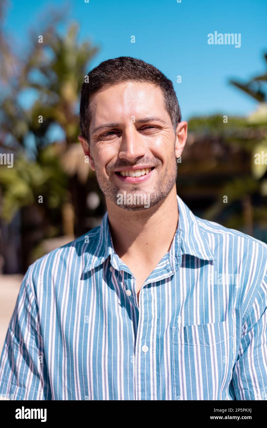 Porträt eines glücklichen weißen Mannes, der in die Kamera schaut und am Strand lächelt Stockfoto
