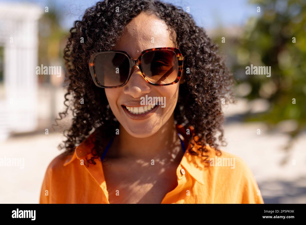 Porträt einer glücklichen afroamerikanischen Frau, die in die Kamera schaut und am Strand lächelt Stockfoto