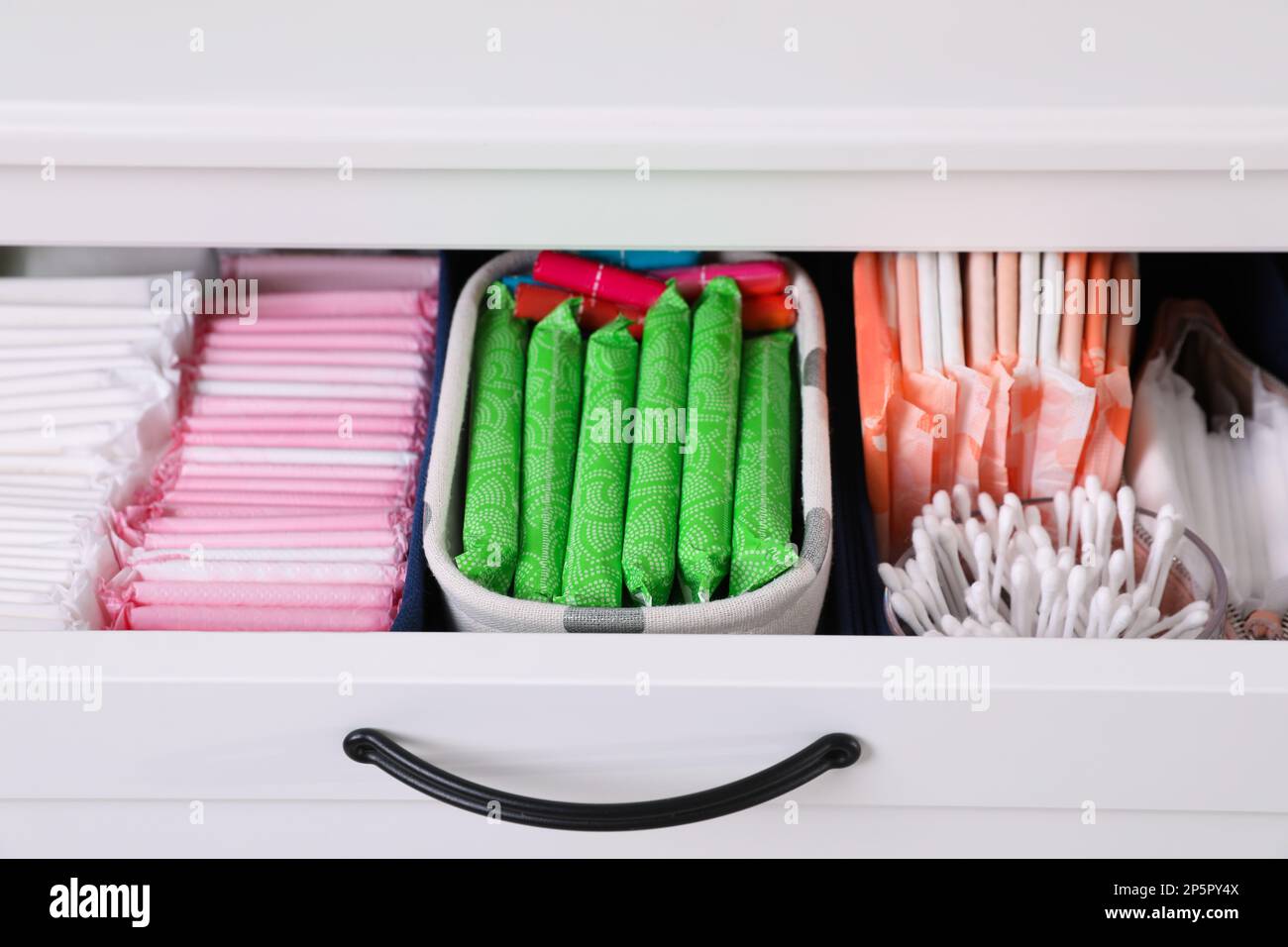 Offene Schrankschublade mit Menstruationsmatten, Tampons und Wattestäbchen, Nahaufnahme Stockfoto