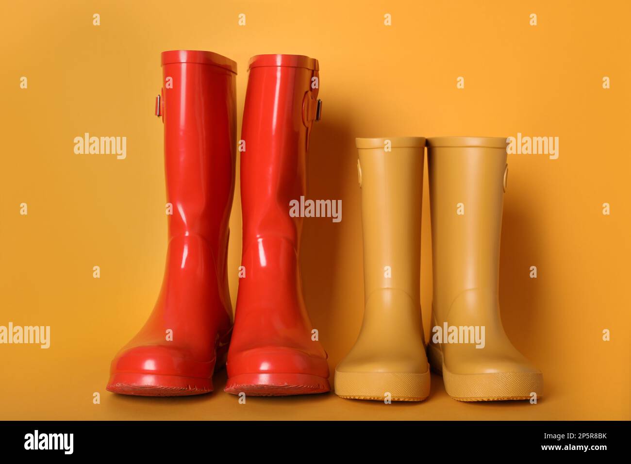 Zwei Paar Gummistiefel auf orangefarbenem Hintergrund Stockfoto