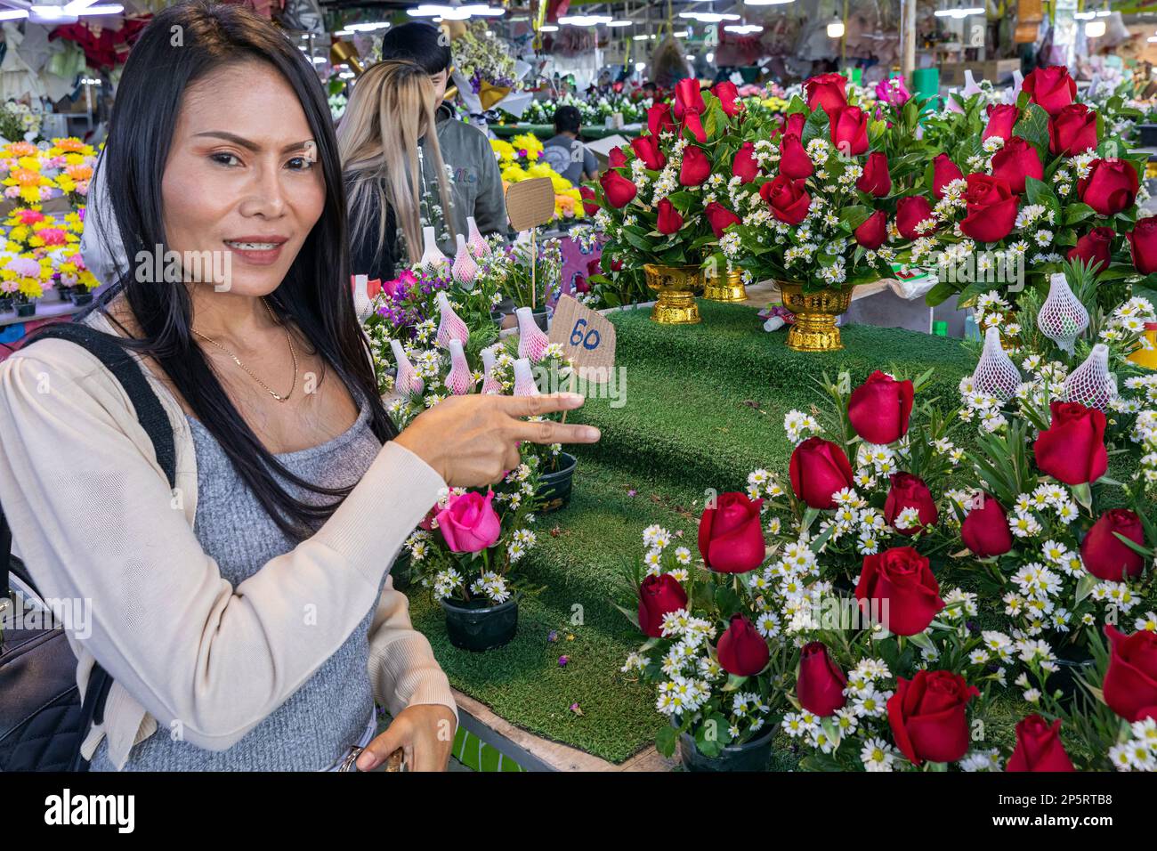 Thailändische Kundin, die Blumen auf dem Pak Khlong Talat Mai Flower Market, Bangkok, Thailand, inspiziert Stockfoto