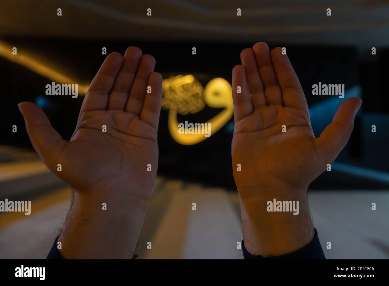 Ramadan oder islamisches Konzeptfoto. Muslimische Gebete mit erhobenen Händen und Kalligraphie im Hintergrund. Selektiver Fokus. Istanbul Turkiye - 11.12.2022 Stockfoto