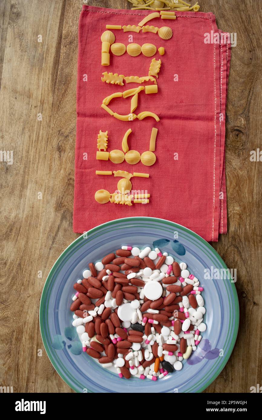 Wellness und Essen mit einem Teller voller Medikamente und das Wort Gesundheit hergestellt mit Pasta Stockfoto