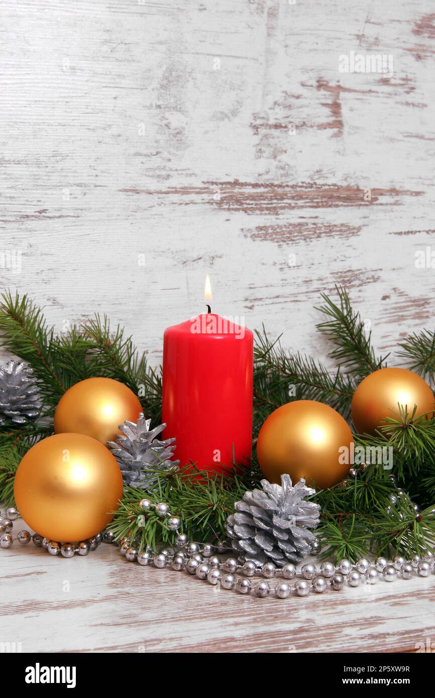 Weihnachtsdekoration mit goldenen Kugeln, roten Kerzen, Pinienzapfen, Fichtenzweigen und silberner Kette Stockfoto