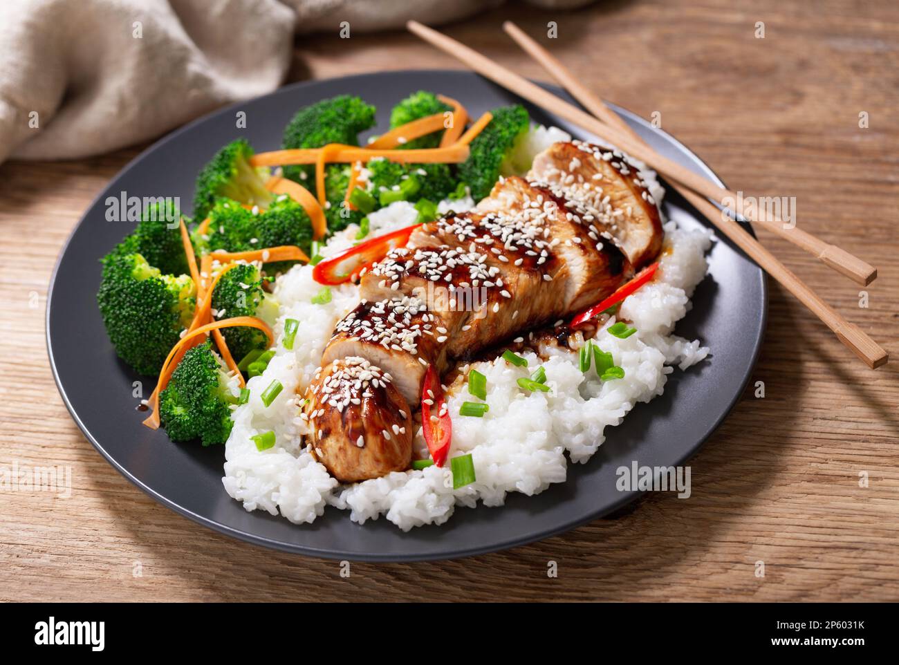 Teller mit Teriyaki-Huhn mit Gemüse und Reis auf einem Holztisch Stockfoto