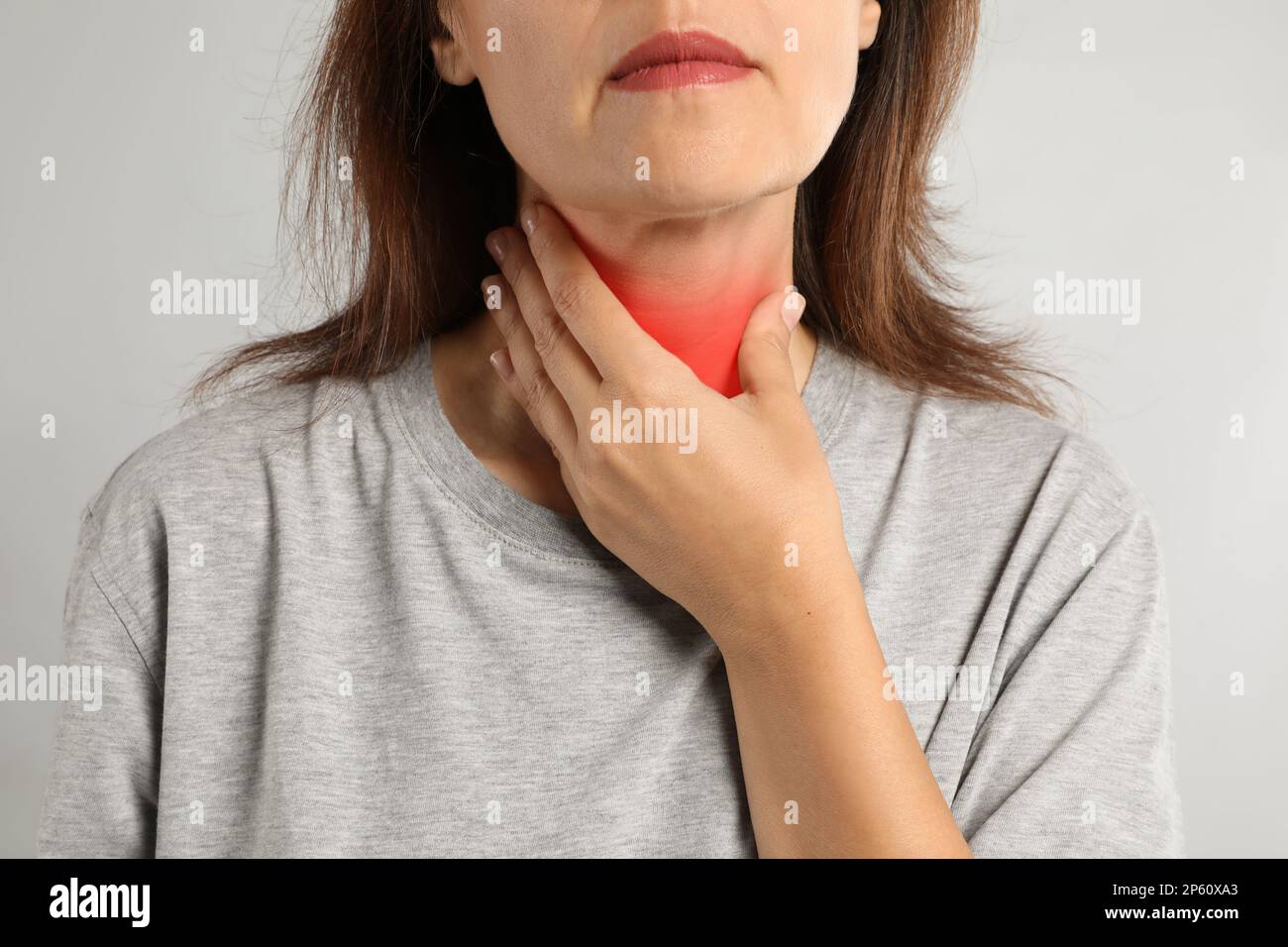 Reife Frau, die Schilddrüsen-Selbstuntersuchung vor hellem Hintergrund macht, Nahaufnahme Stockfoto