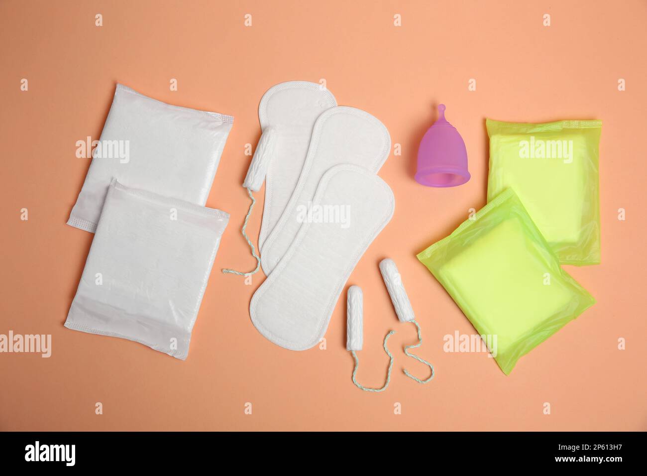 Menstruationseinlagen und andere Periodenprodukte auf blassorangefarbenem Hintergrund, flach liegend Stockfoto