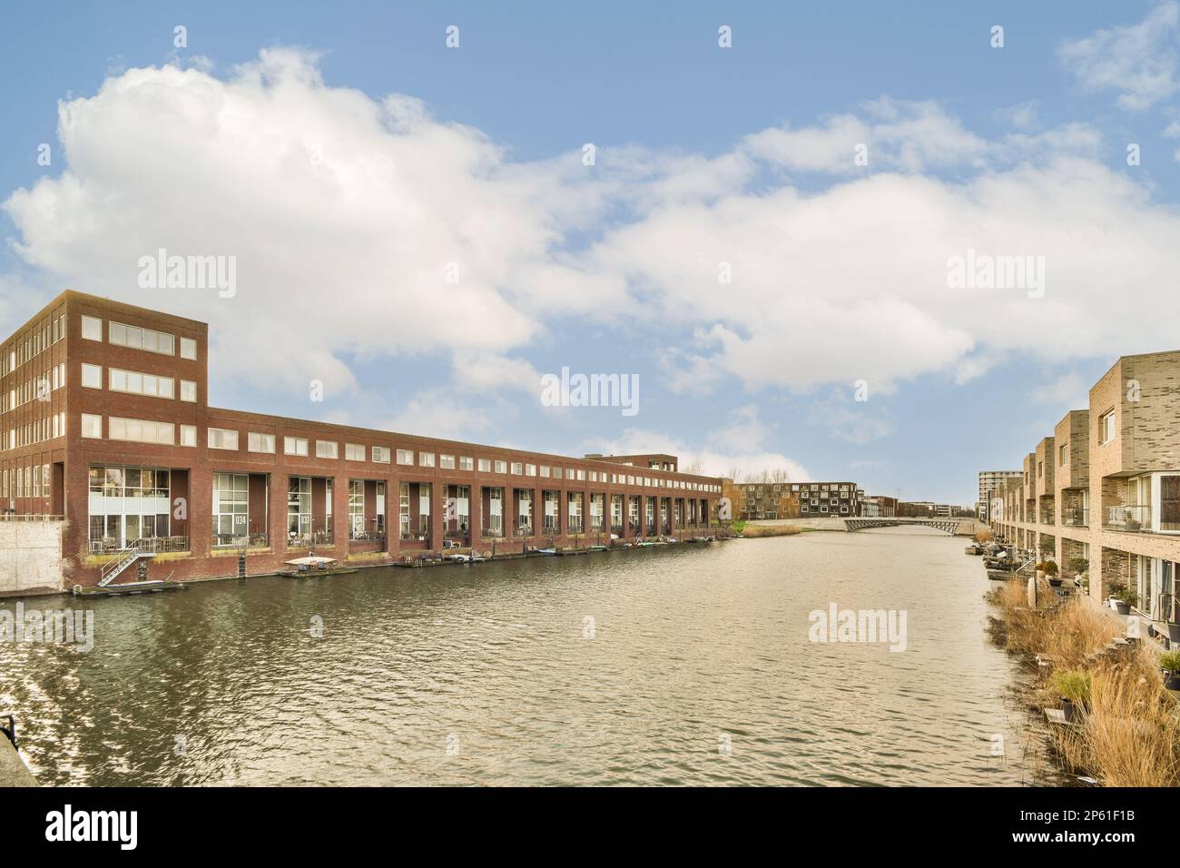 Einige Gebäude an der Seite eines Wasserkörpers mit Wolken am Himmel über ihnen und Häuser entlang Stockfoto