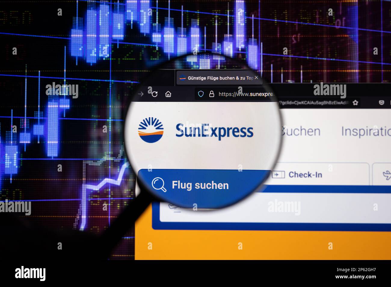 Sun Express, Firmenlogo einer Fluggesellschaft auf einer Website mit verschwommenen Entwicklungen am Aktienmarkt im Hintergrund, auf einem Bildschirm durch eine Lupe zu sehen Stockfoto