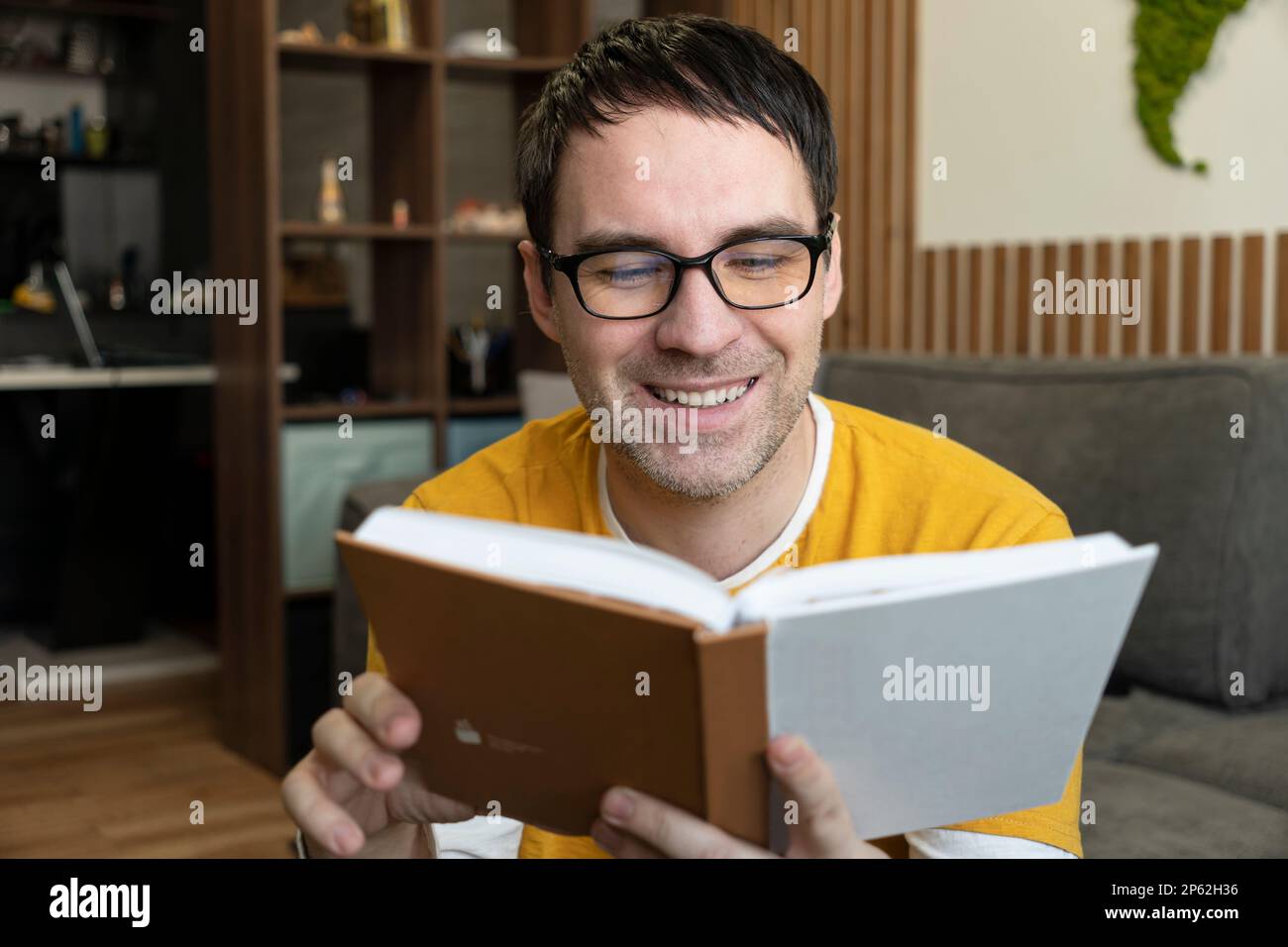 Ein junger Mann liest zu Hause ein Buch Stockfoto