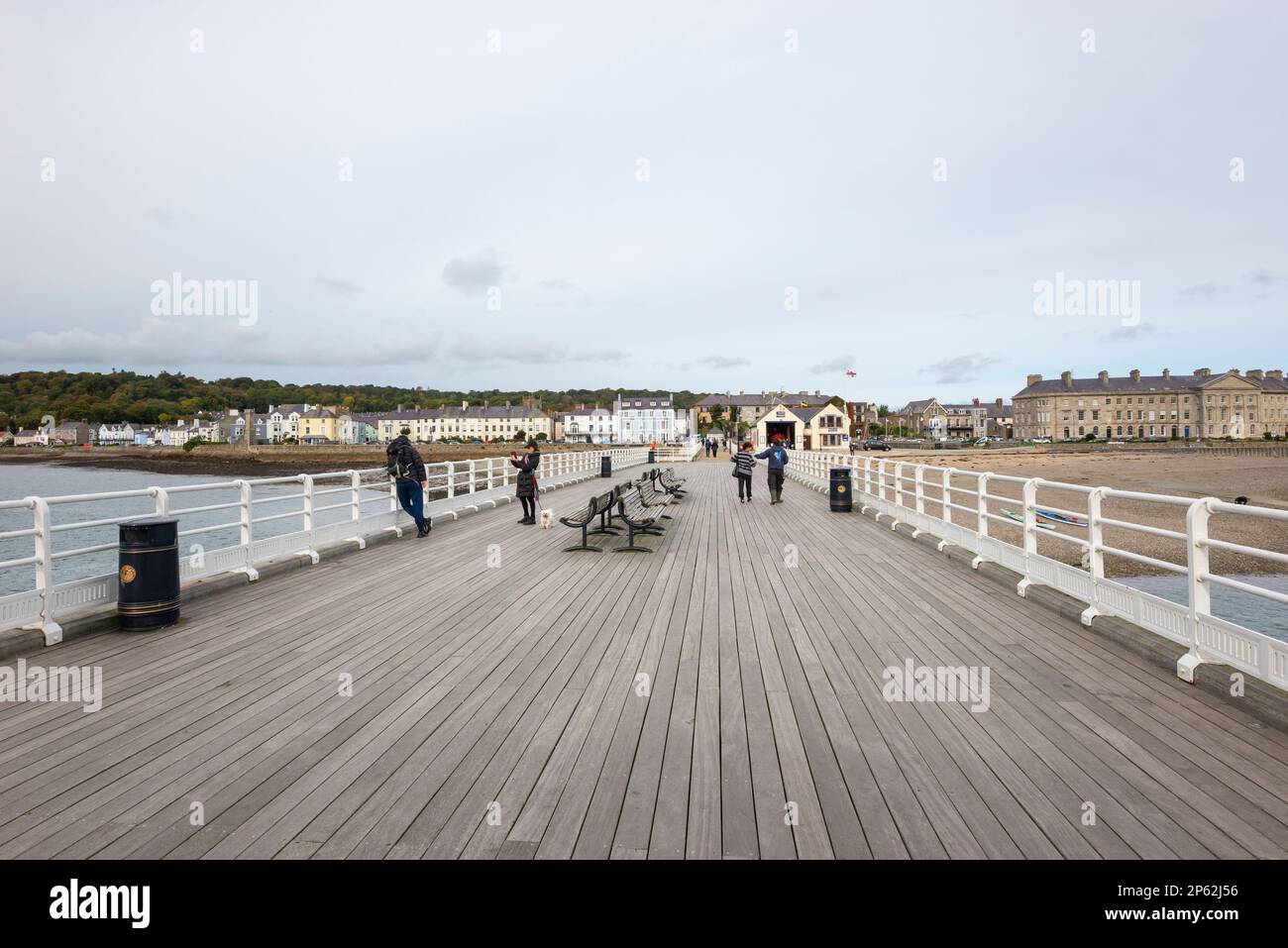 Touristen auf dem historischen Pier in Beaumaris mit Blick zurück auf die Stadt Anglesey, Nordwales. Stockfoto