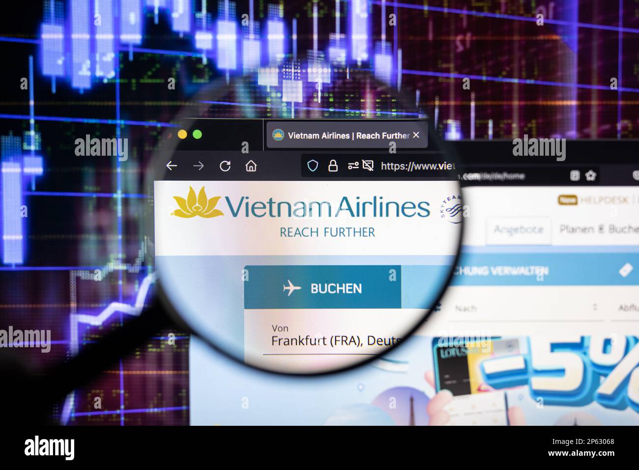 Vietnam Airlines Firmenlogo auf einer Website mit verschwommenen Aktienmarktentwicklungen im Hintergrund, auf einem Bildschirm durch eine Lupe zu sehen Stockfoto