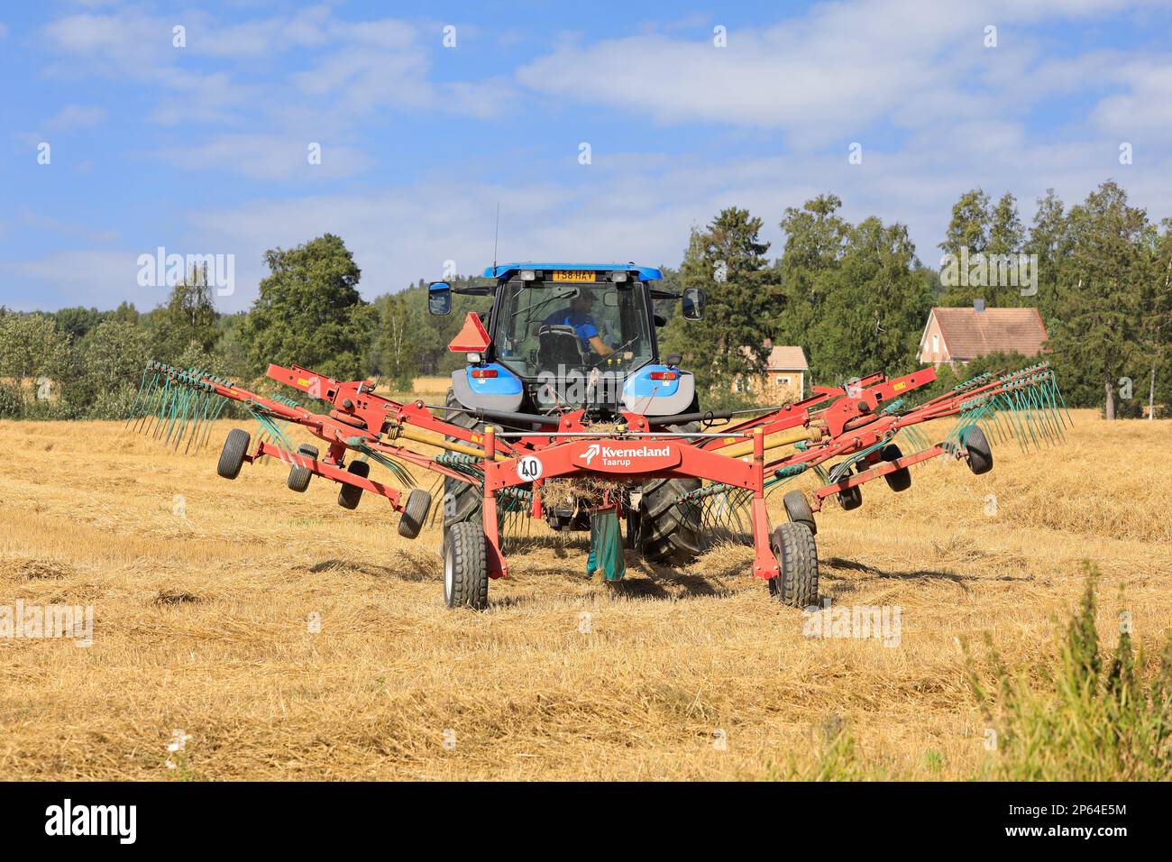 Landwirt, der auf dem Feld mit Traktor und Kverneland Taarup Zwillingsrechen arbeitet und an einem Tag im Spätsommer trockenes Stroh harkt. Salo, Finnland. 27. August 2022. Stockfoto