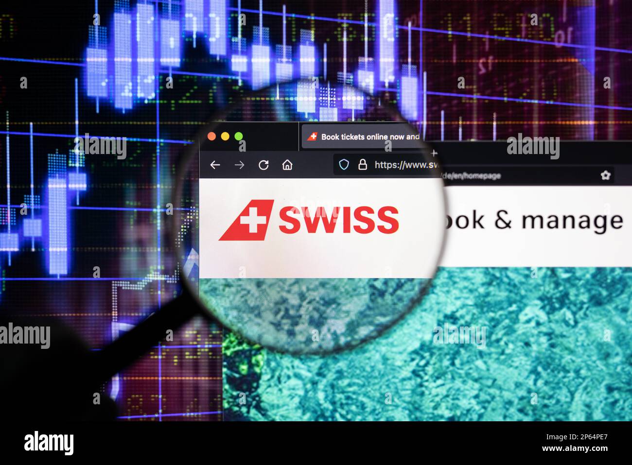 Logo der Swiss Air Company auf einer Website mit verschwommenen Aktienmarktentwicklungen im Hintergrund, auf einem Computerbildschirm durch eine Lupe zu sehen Stockfoto